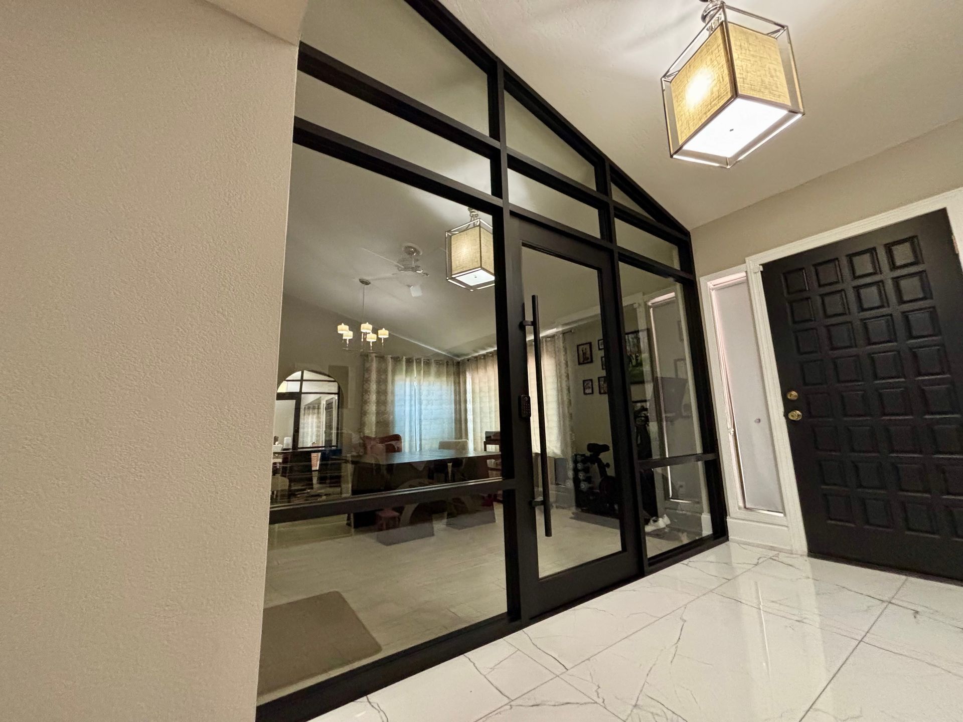 Entryway with large glass windows and black trim, leading to a living area. Black front door on the right.