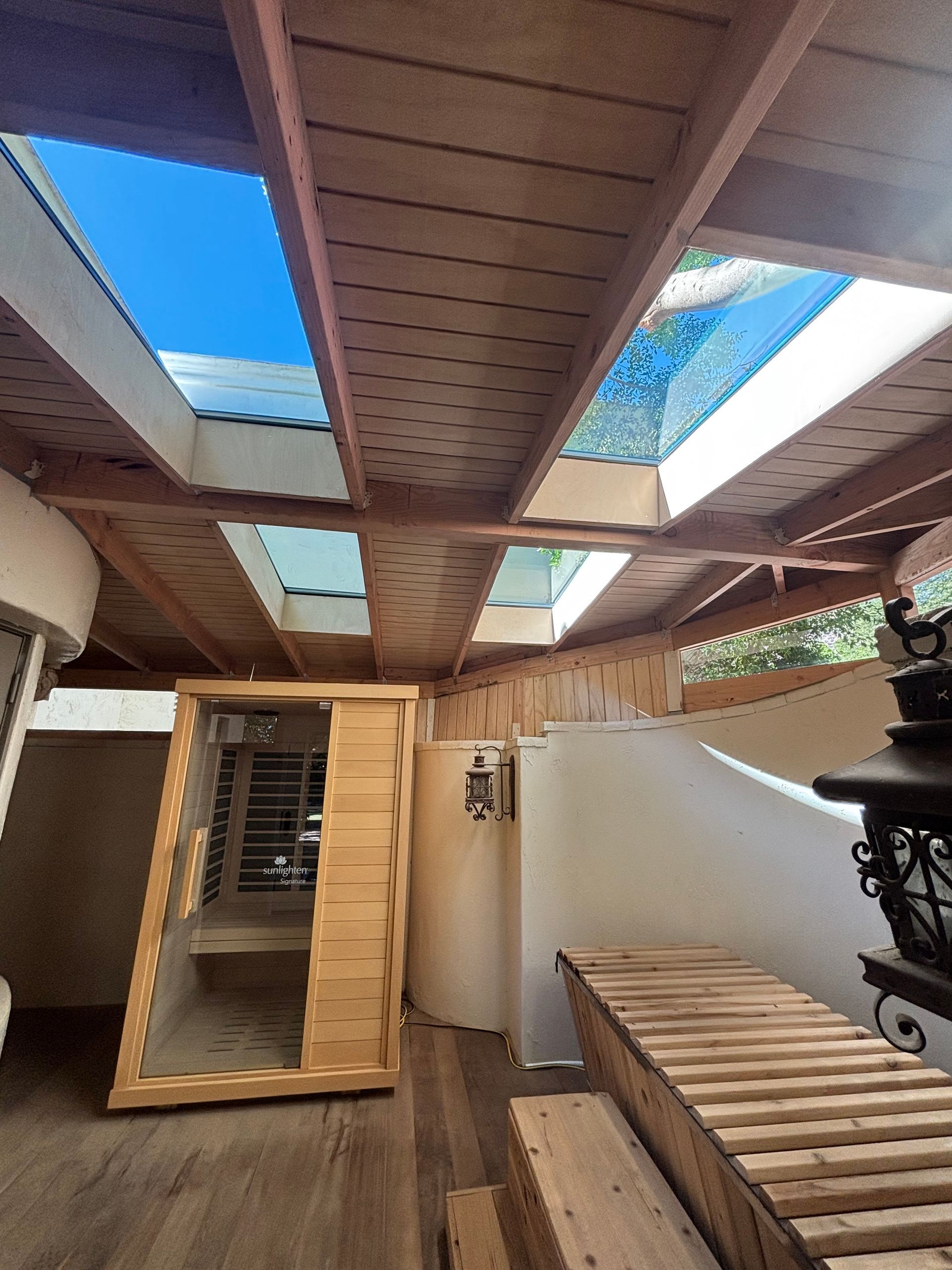 Wooden sauna with skylights, benches, and outdoor views of blue sky.