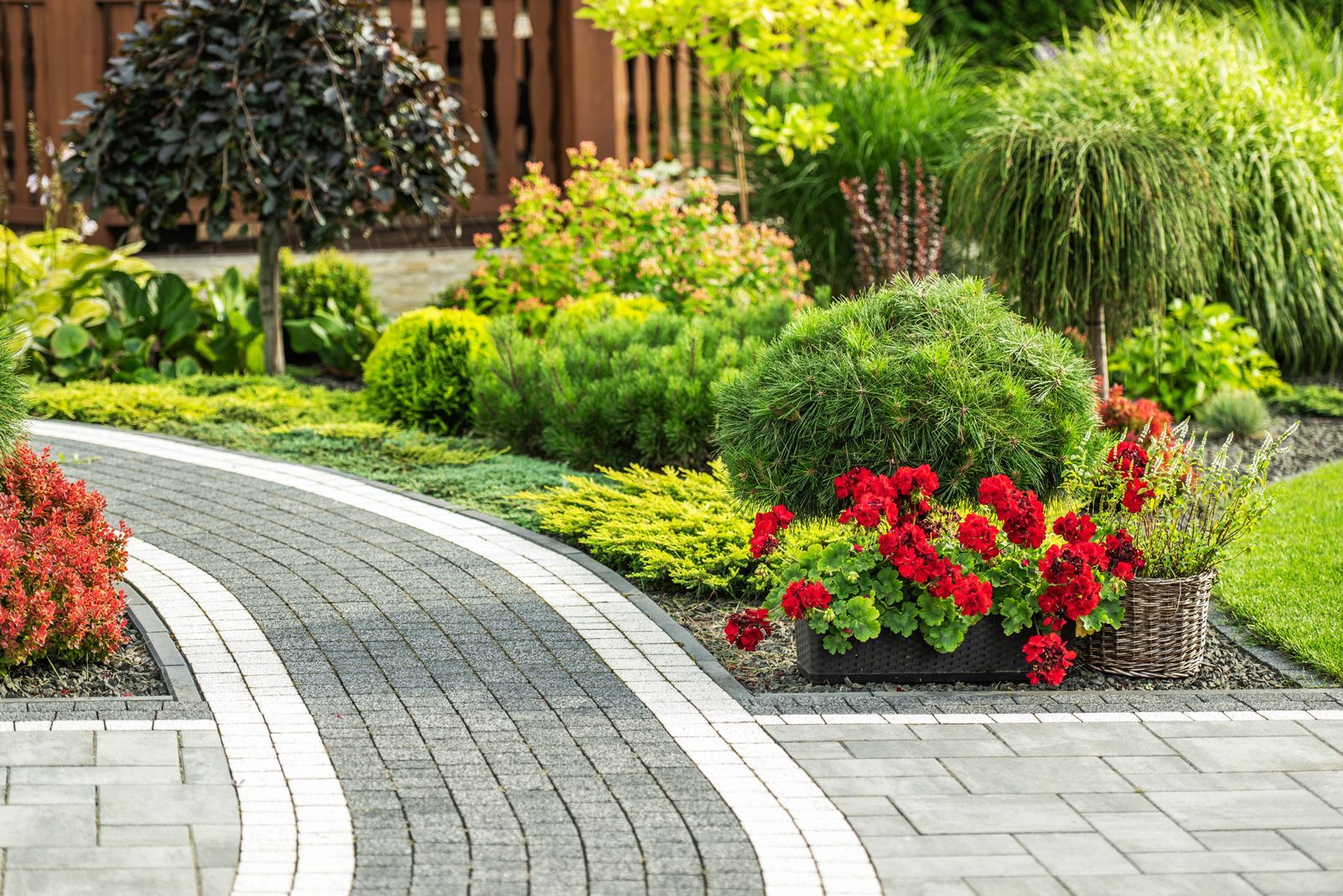 A brick walkway surrounded by flowers and trees in a garden.
