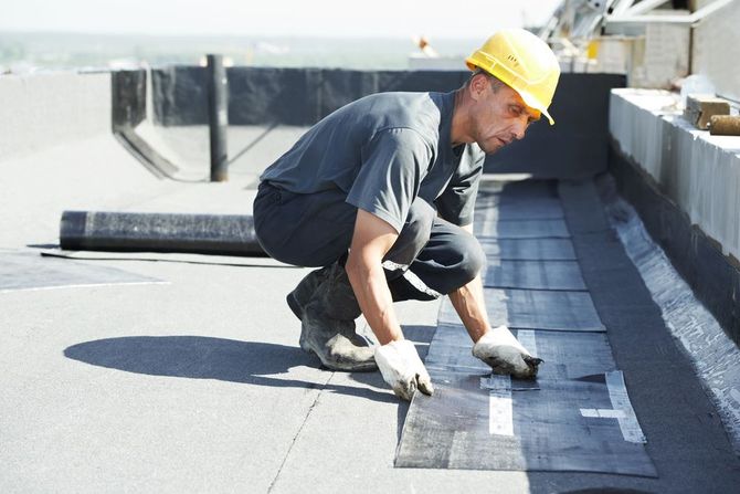 Roofer installing flat roof membrane