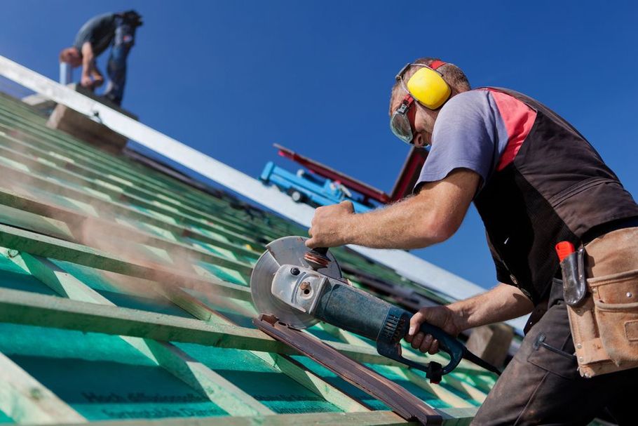 Roofer using angle grinder on roof structure.