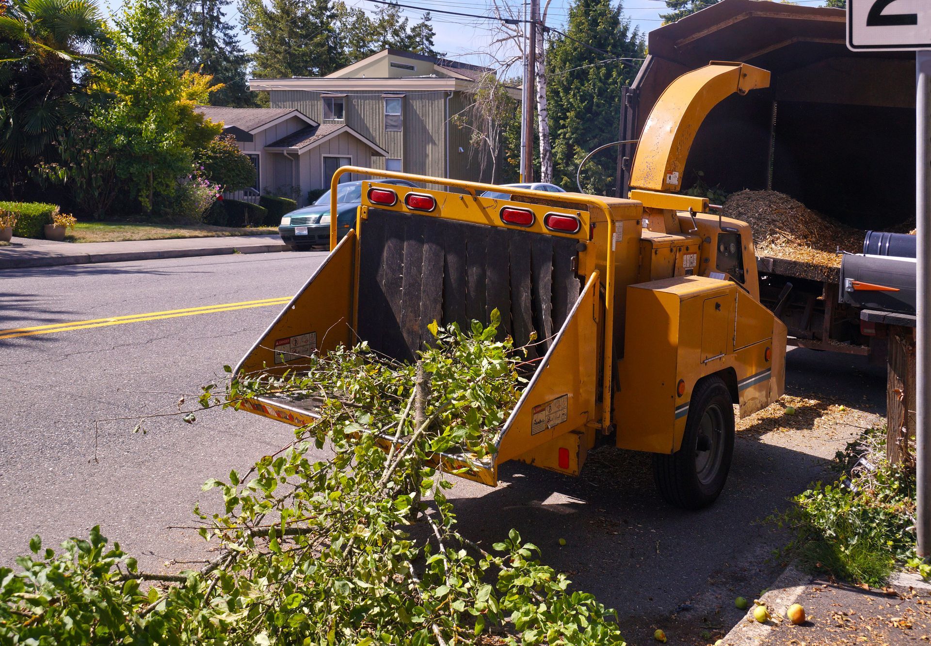 Wood chipper in action, turning branches into wood chips during suburban cleanup.