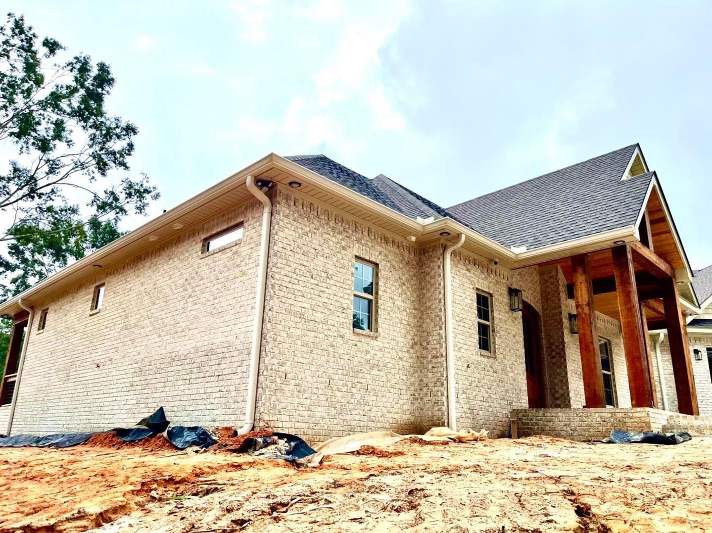 Newly constructed brick house with brown trim and exposed wooden beams.