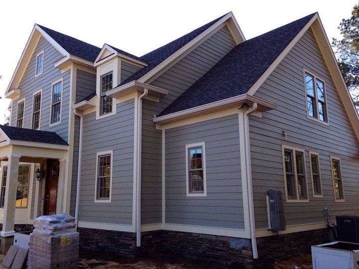 Gray house with beige trim and dark roof under construction.