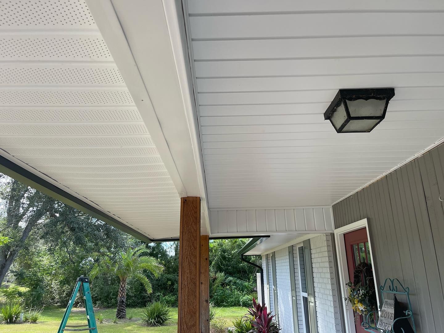 White porch ceiling with a light fixture and a brown support beam.