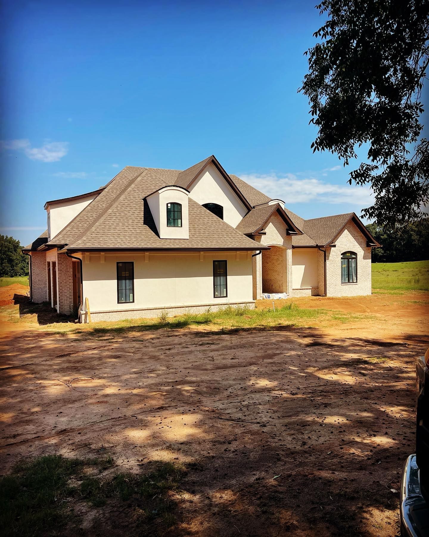 Newly constructed house with tan stucco, brown roof, and blue sky.