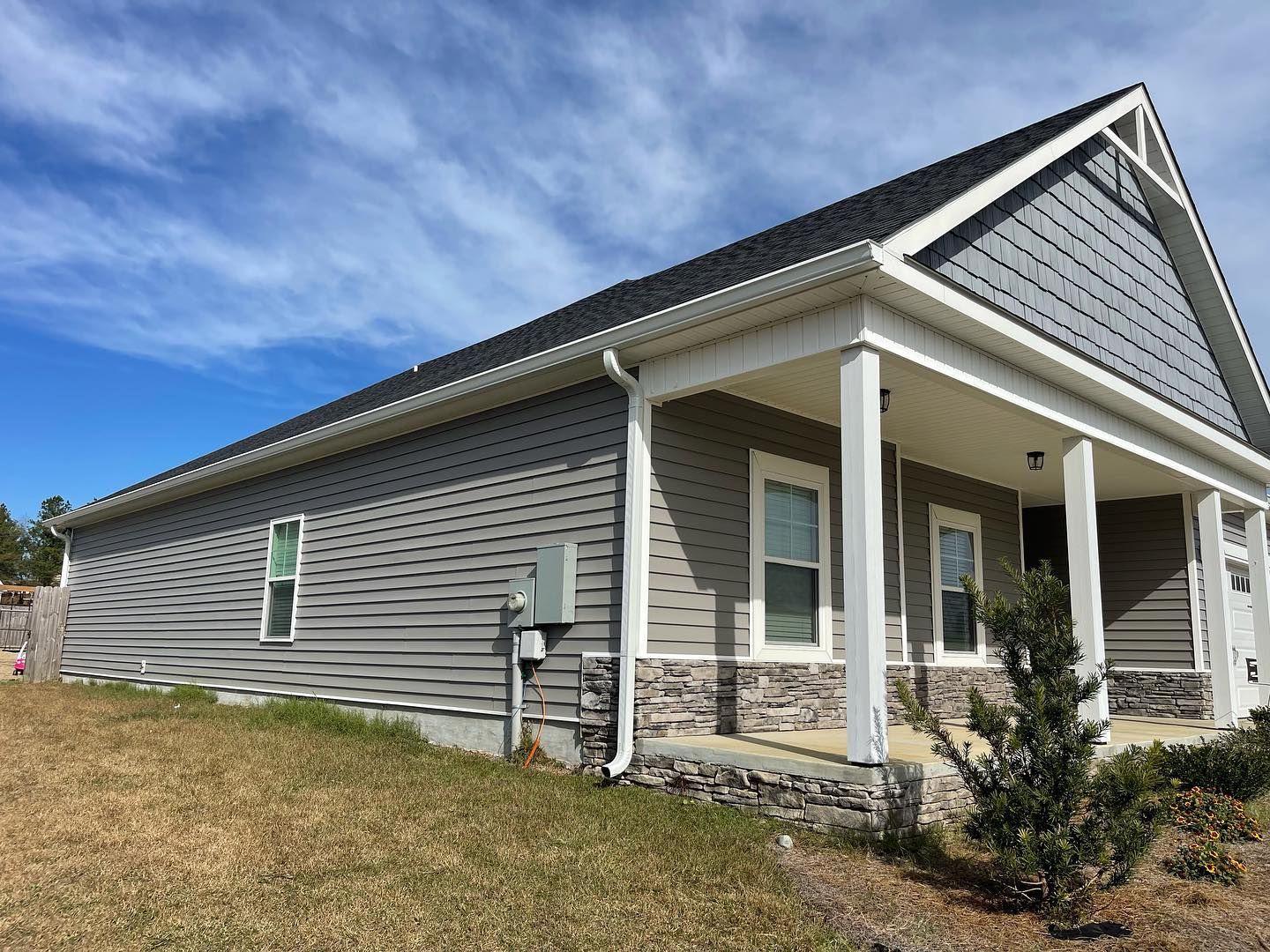 Gray house with a porch and blue sky.