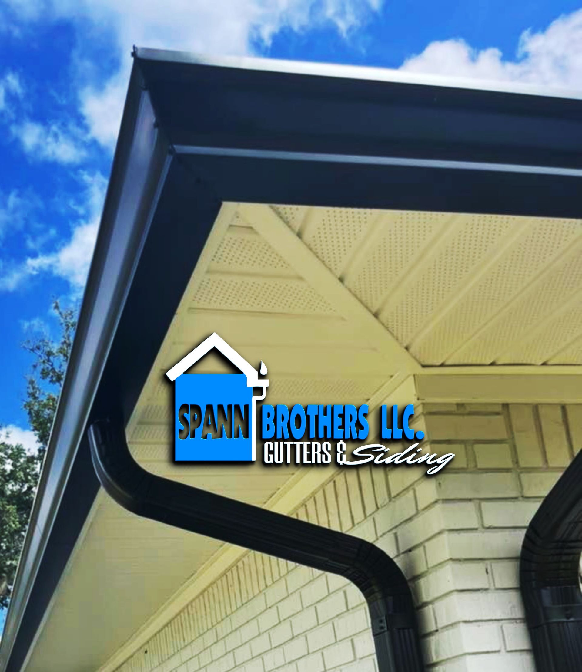 Garage with black doors, white brick, stone accents, and a dark roof under a blue sky.