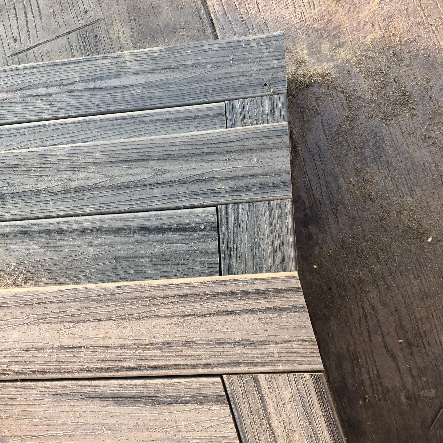 Close-up of gray-toned wood deck with sand along the edge.