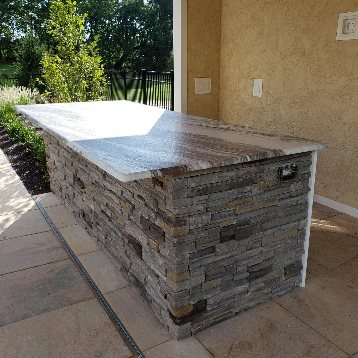 Stone outdoor kitchen island with granite countertop.