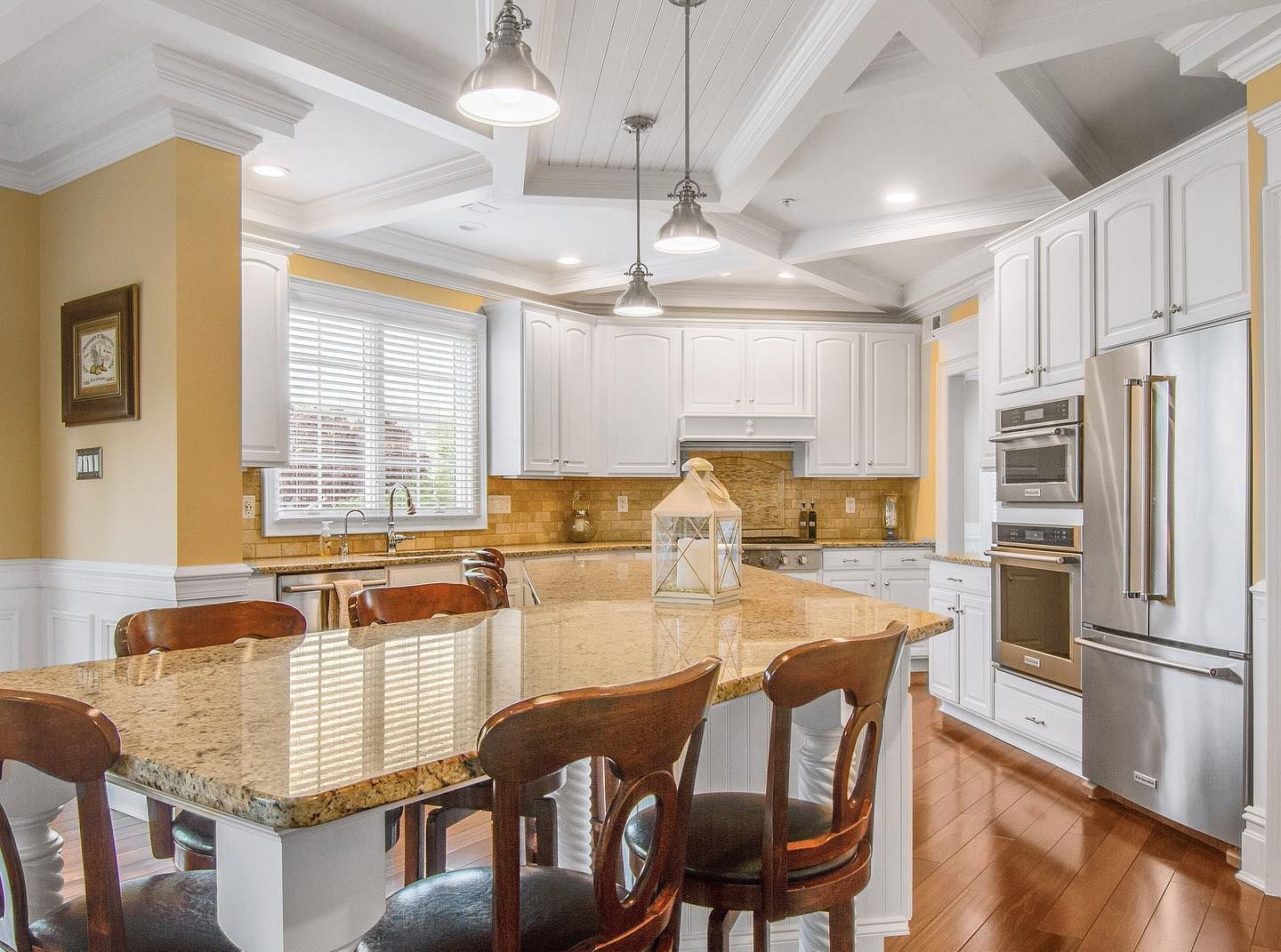 Bright kitchen with white cabinets, granite countertops, and wood table with chairs.