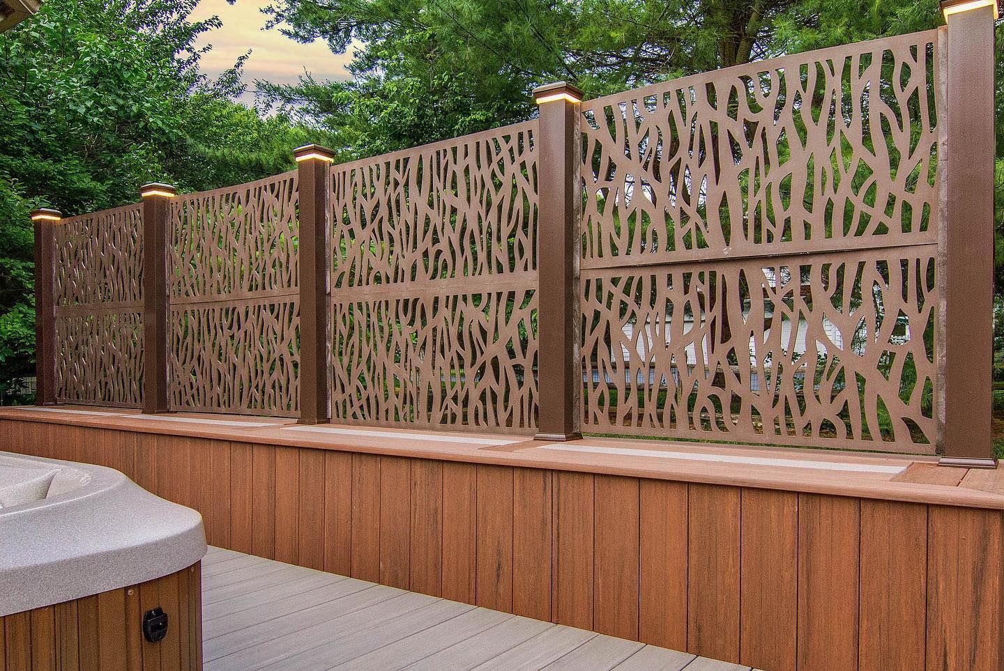 Brown privacy fence with laser-cut organic pattern on a wooden deck, with lights on top.
