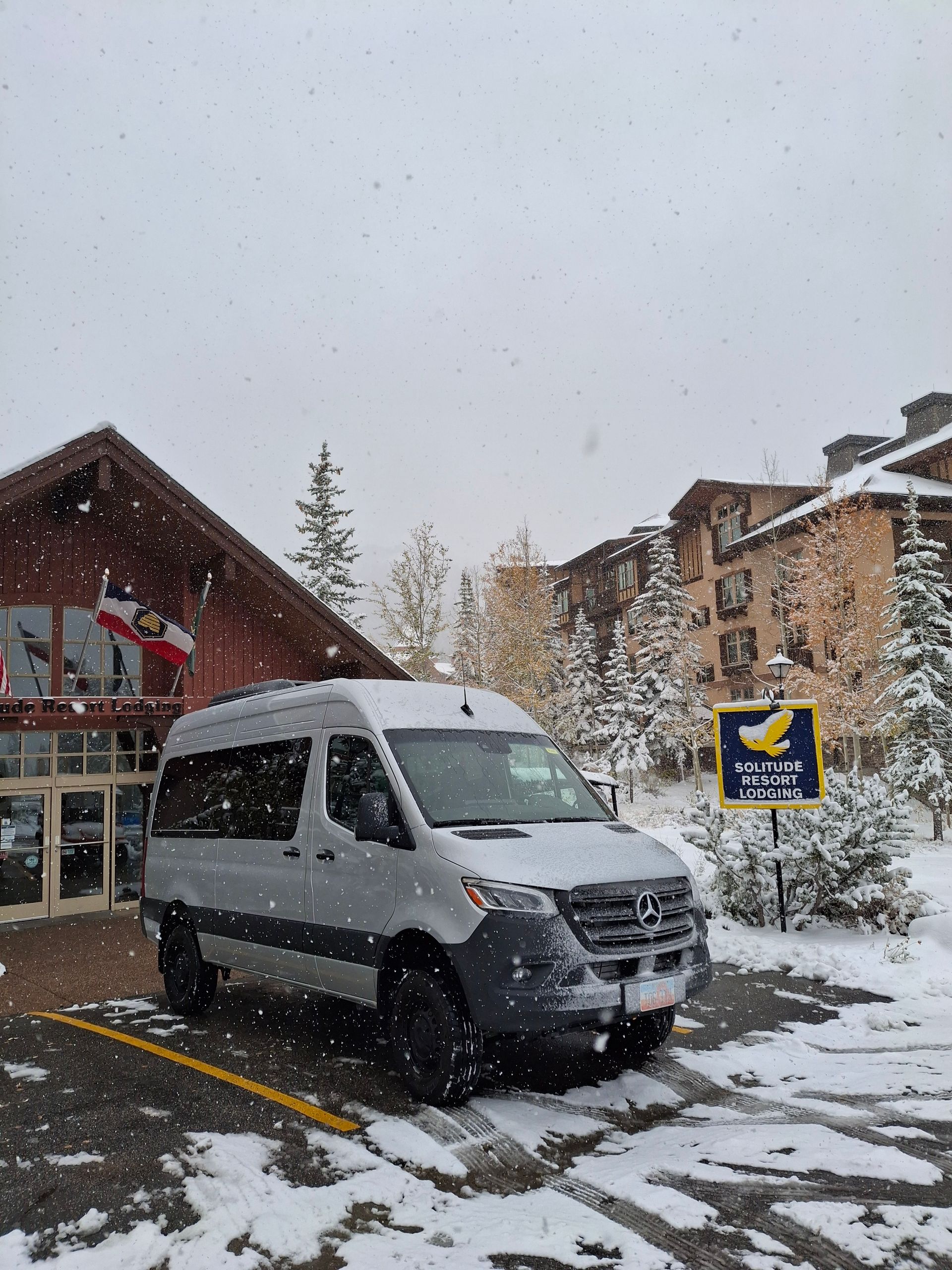 A black van is driving down a snowy mountain road.