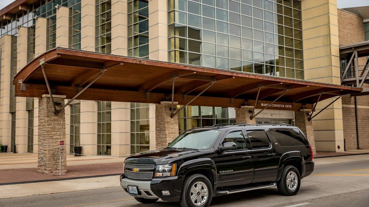 A black suv is parked in front of a large building.