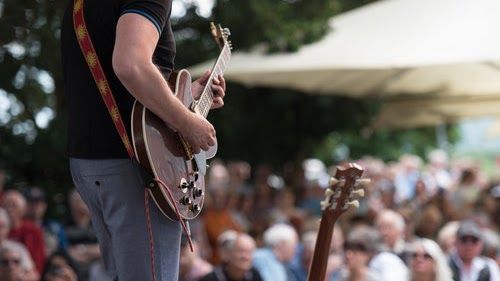 A man is playing a guitar in front of a crowd.