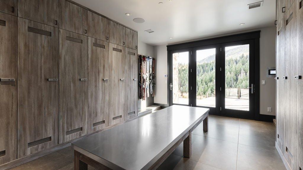 A locker room with lots of wooden lockers and a long table.