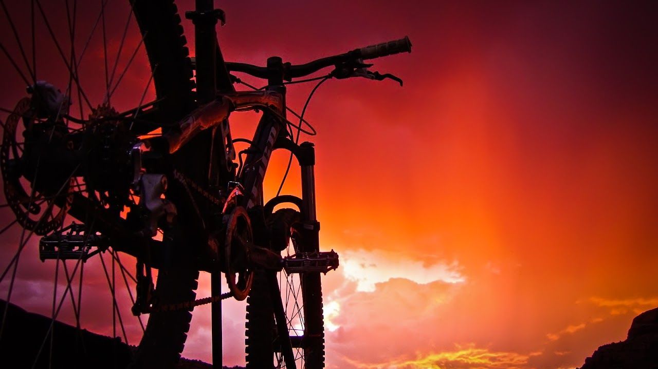 A bicycle is silhouetted against a sunset sky.