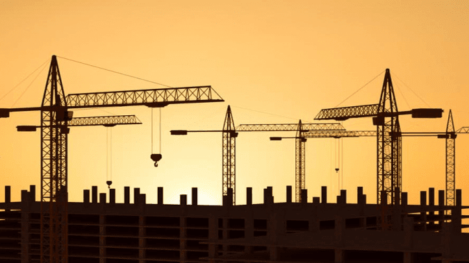 A construction site with cranes and buildings in the background