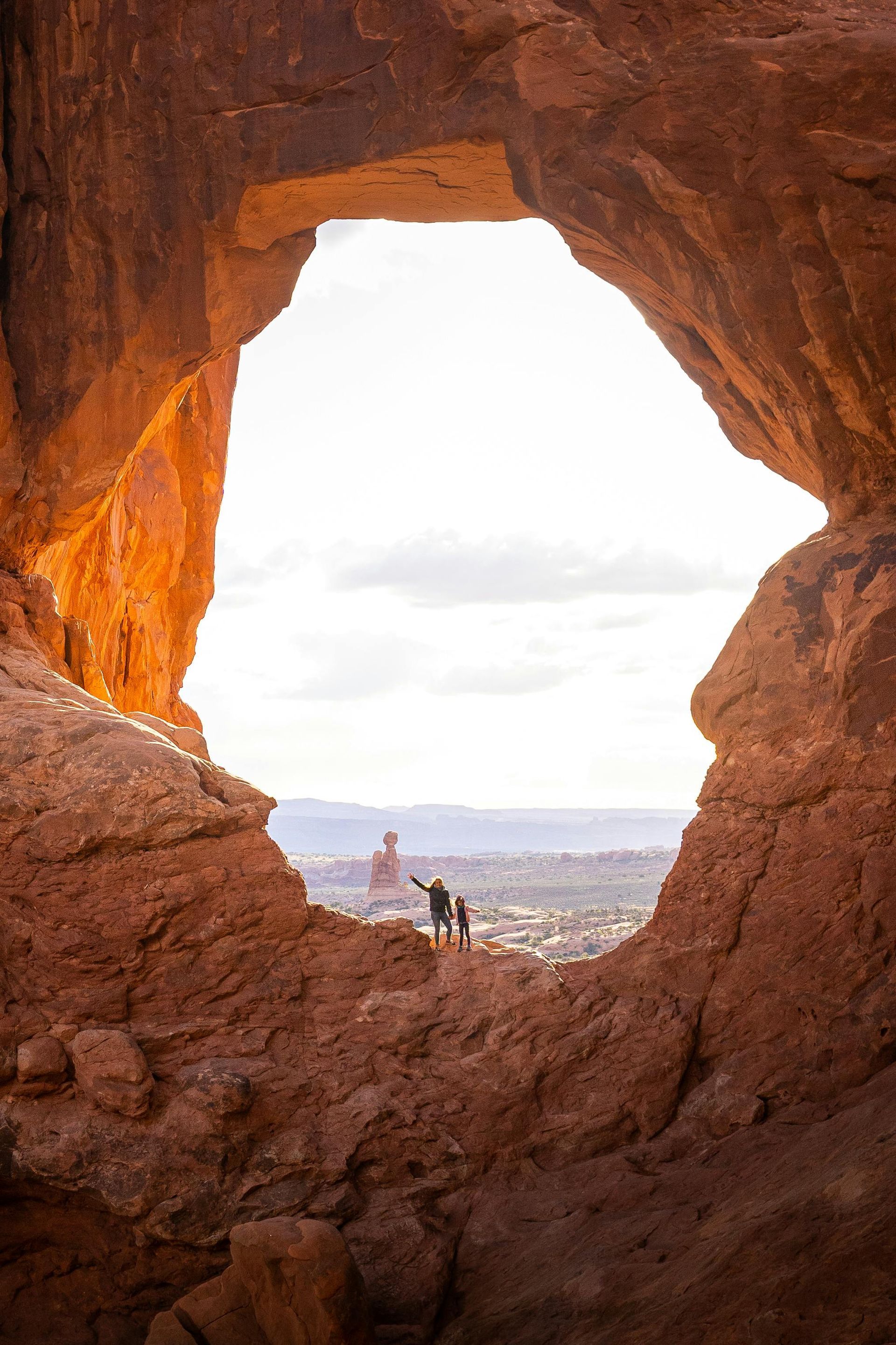 A couple standing in a cave with a view of the desert.