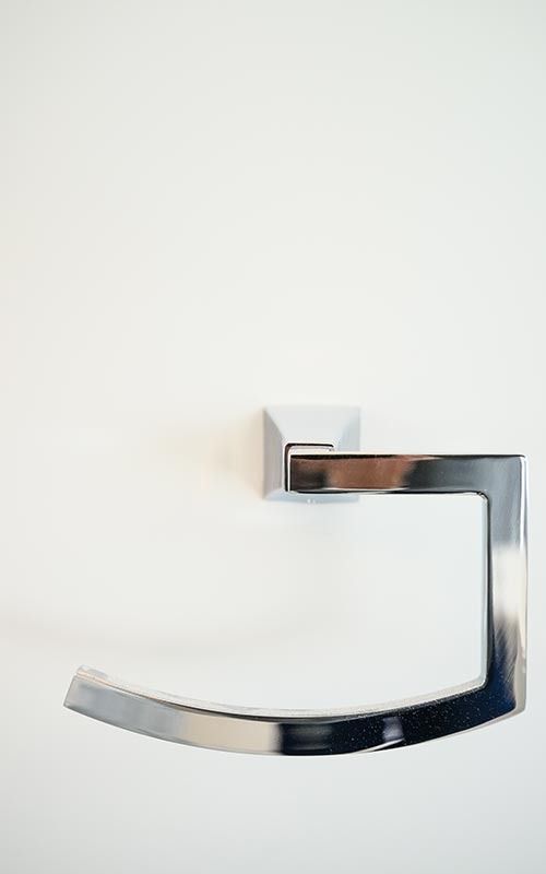 A polished chrome, C-shaped towel ring mounted on a plain white wall.