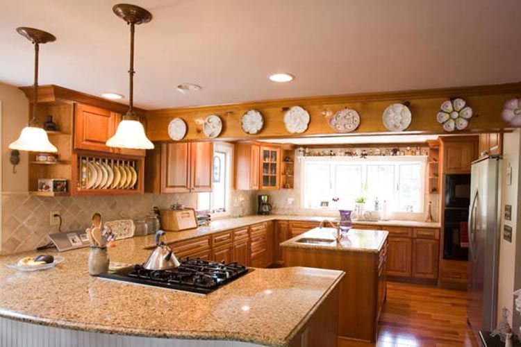 A spacious kitchen features wood cabinets, granite countertops, a central island, and decorative plates on a wall ledge.