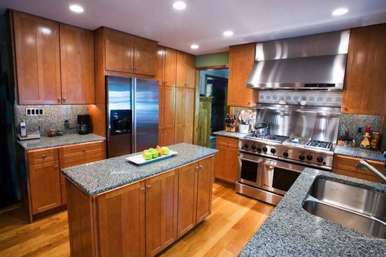 Kitchen featuring wood cabinets, stainless steel appliances, granite countertops, and a central island with fruit.