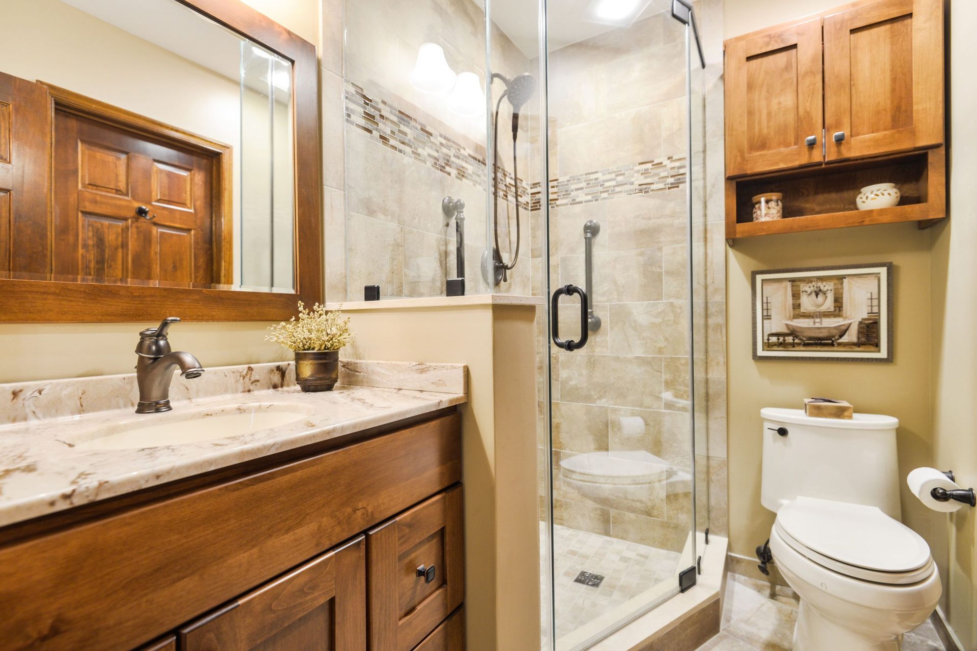 A rustic-style bathroom with a wooden vanity, a stone countertop, a corner glass shower, and a toilet under wall cabinets.