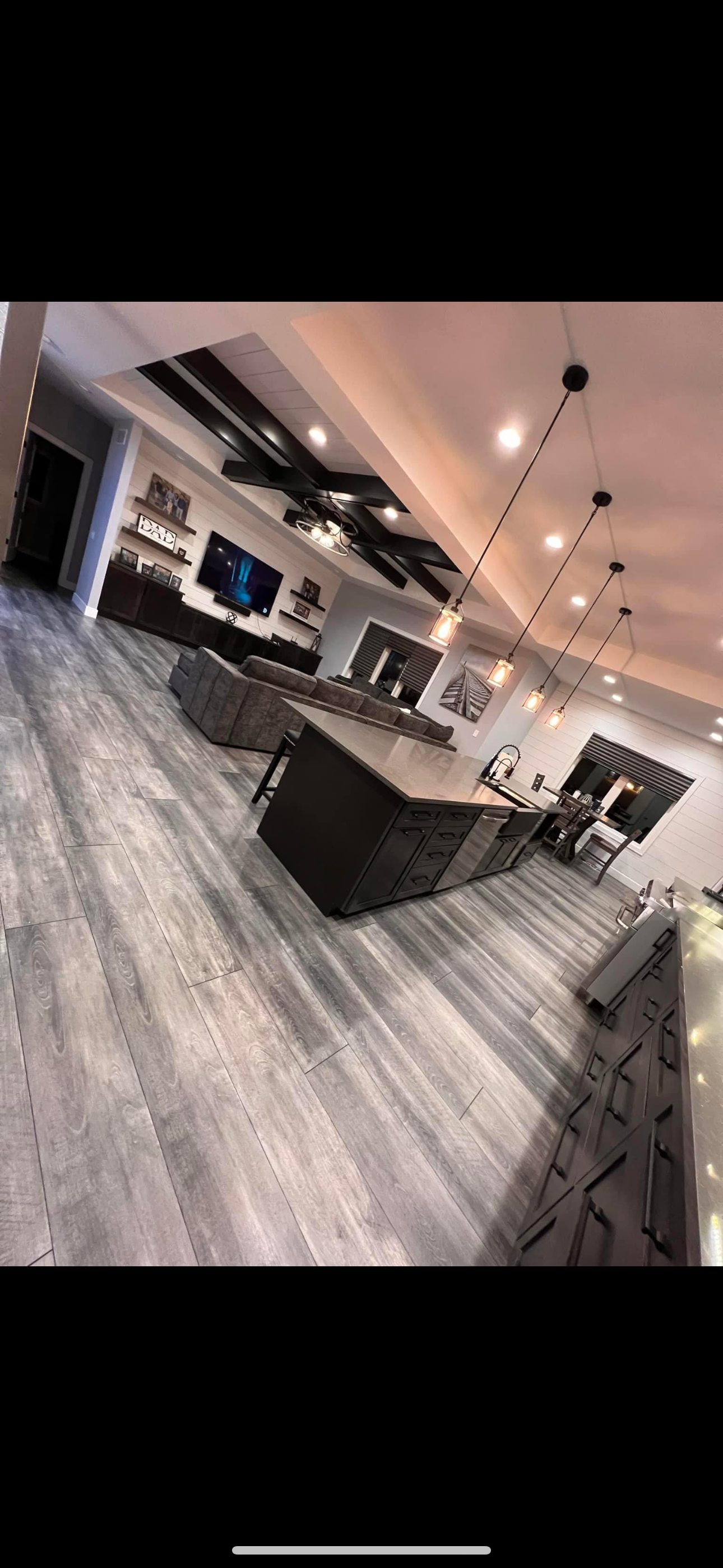 Spacious modern kitchen with dark island, light wood floors, and ceiling lights.