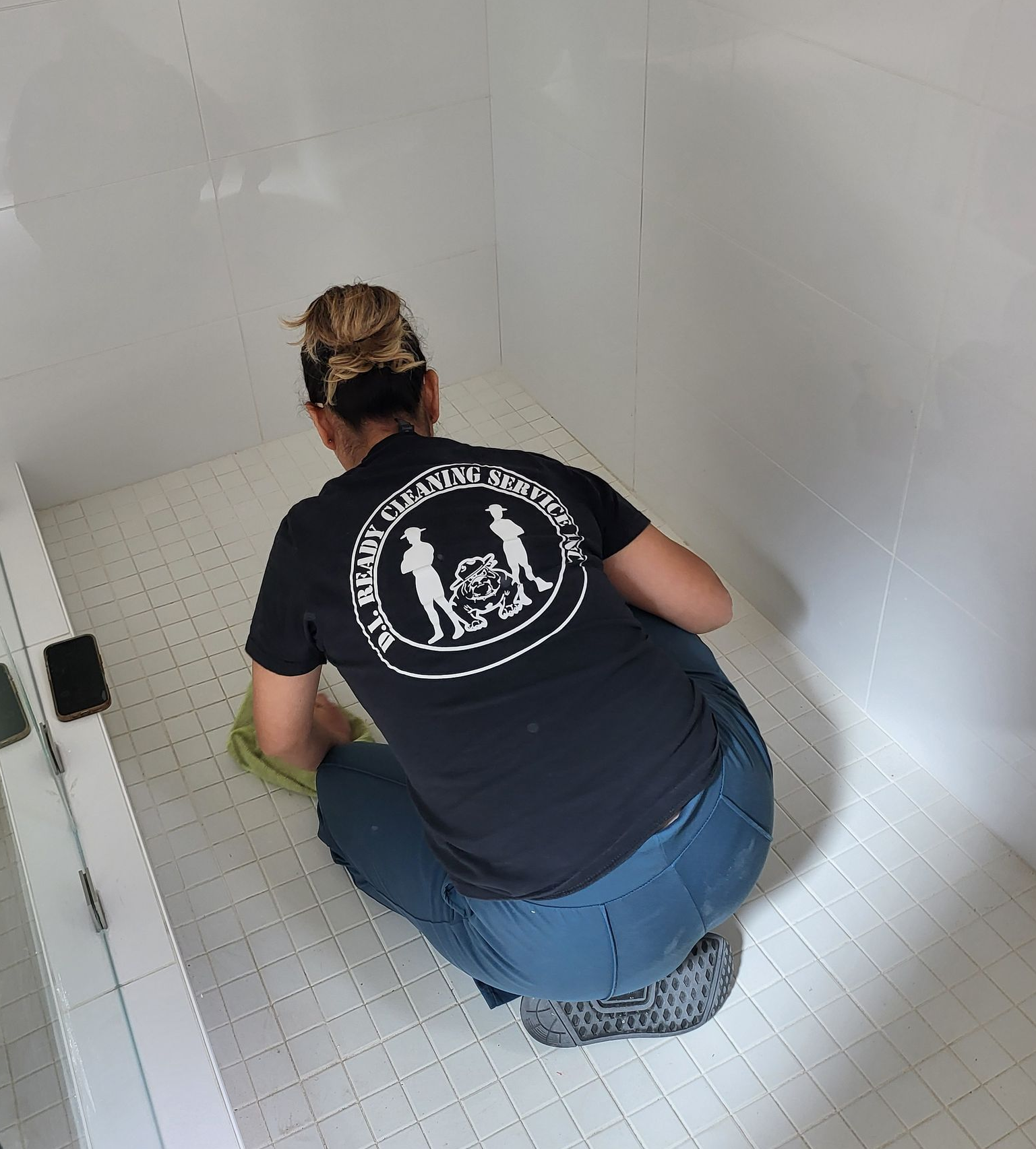 A mop cleaning a wet wooden floor in an office, yellow caution sign in background.