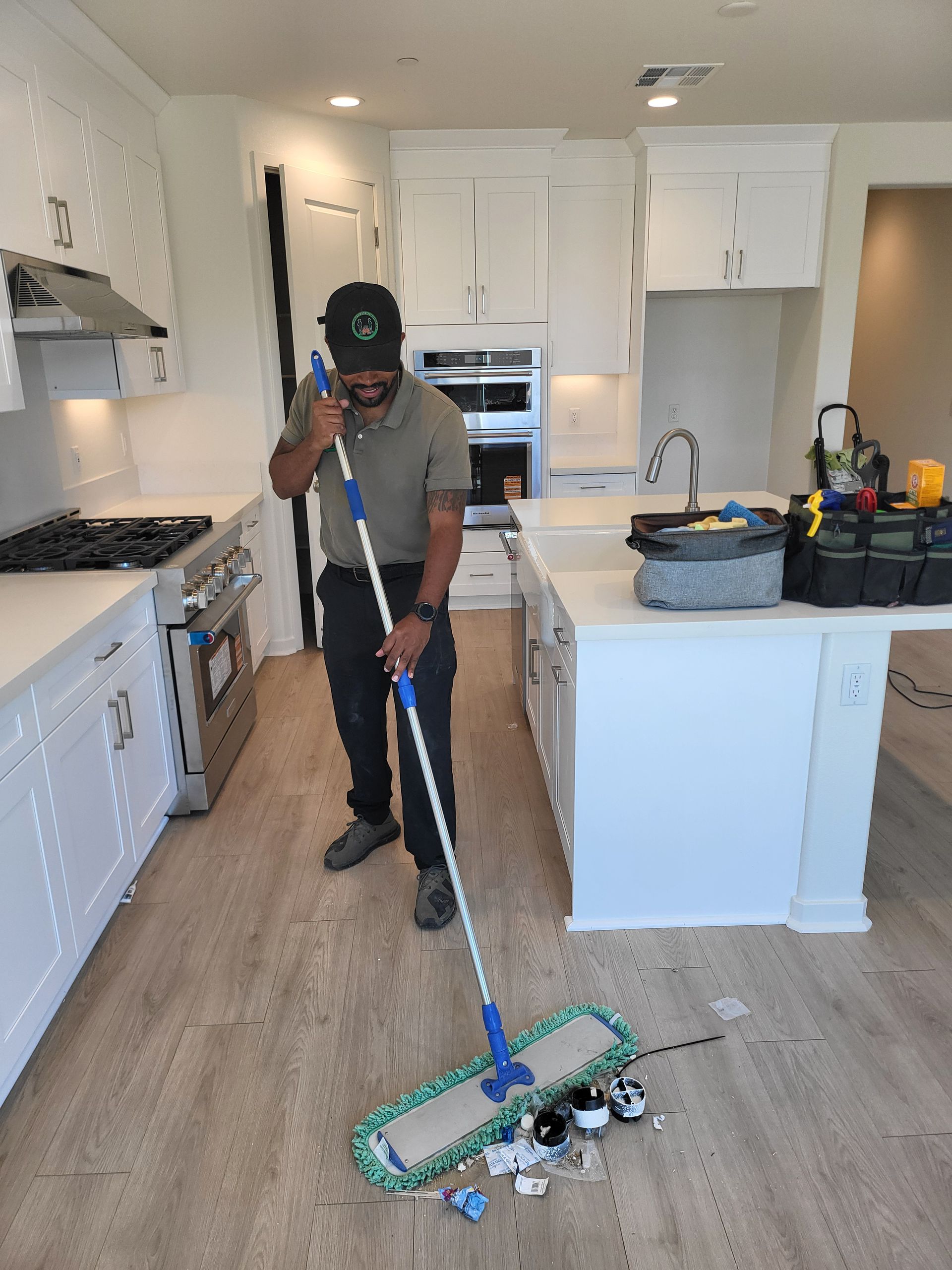 Person in blue cleaning a hotel room carpet with a vacuum cleaner.