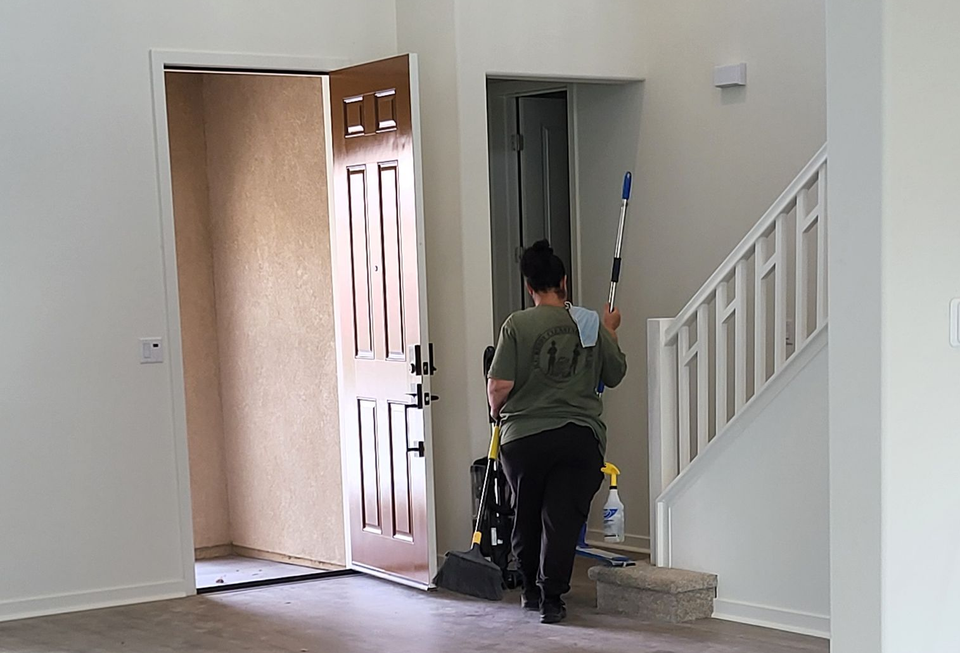 Person wearing blue gloves using a vacuum cleaner to clean an office chair.