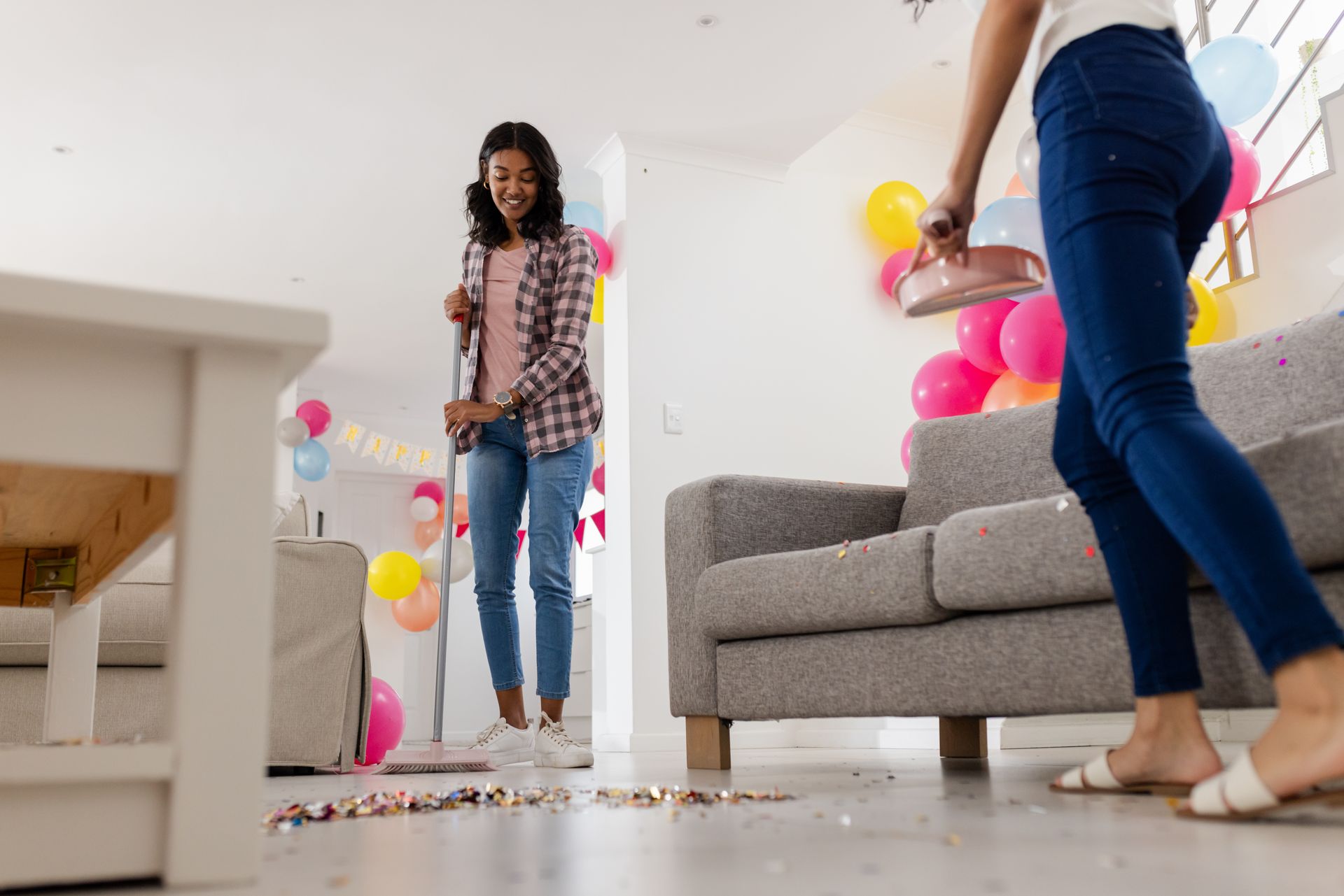 Person in white pants and clogs mopping a stone hallway with a long-handled mop.