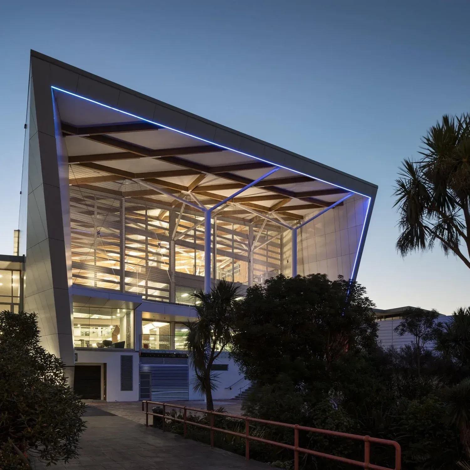 Modern building with illuminated glass facade, blue night sky.