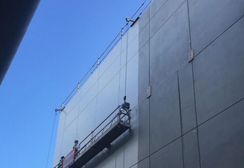 Construction platform suspended on the side of a building, blue sky above.