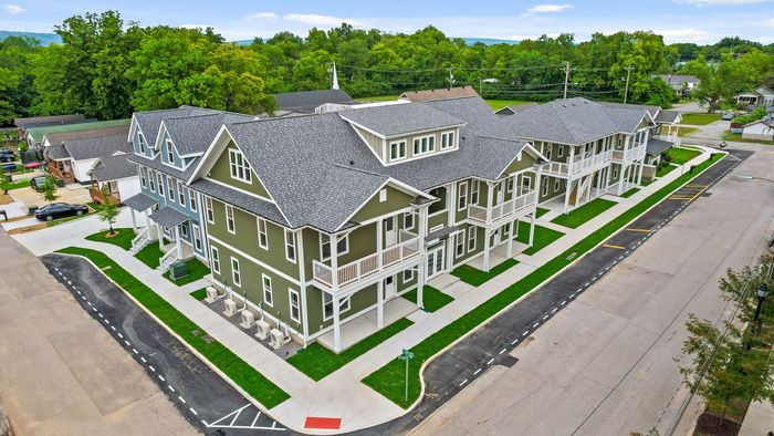 Two-story apartment buildings with white and yellow exteriors, each with a covered porch, sit along bailey avenue.