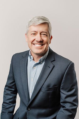 Man in blue blazer and shirt smiles at the camera.