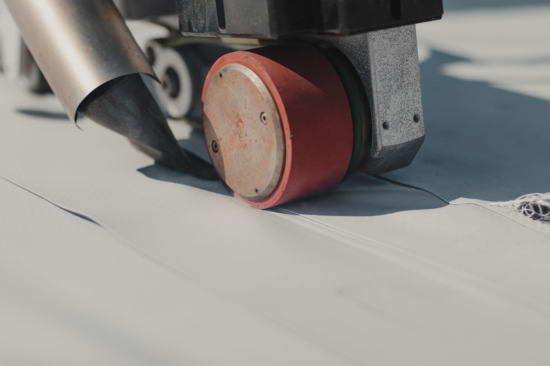 A close up of a machine with a red wheel on a roof.