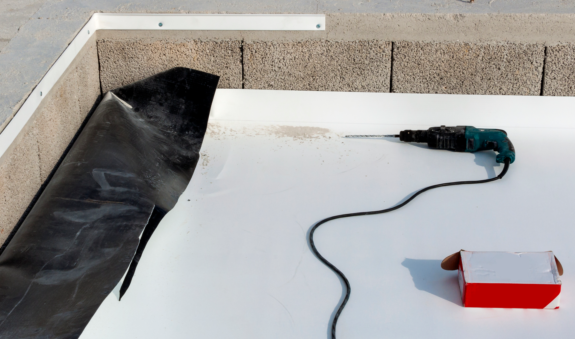 A drill is sitting on a white surface next to a box.