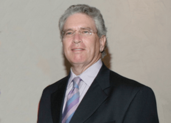 A man in a suit and tie is smiling for the camera