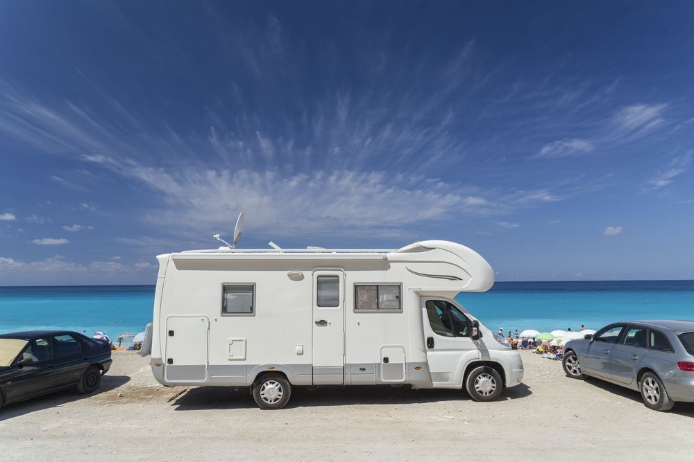 White Rv Parked on a Beach With Blue Ocean and Sky — The Caravan Clinic in Tweed Heads, NSW