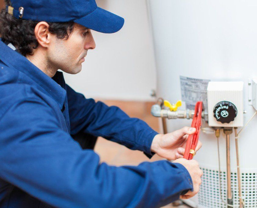 A man is fixing a water heater with a wrench