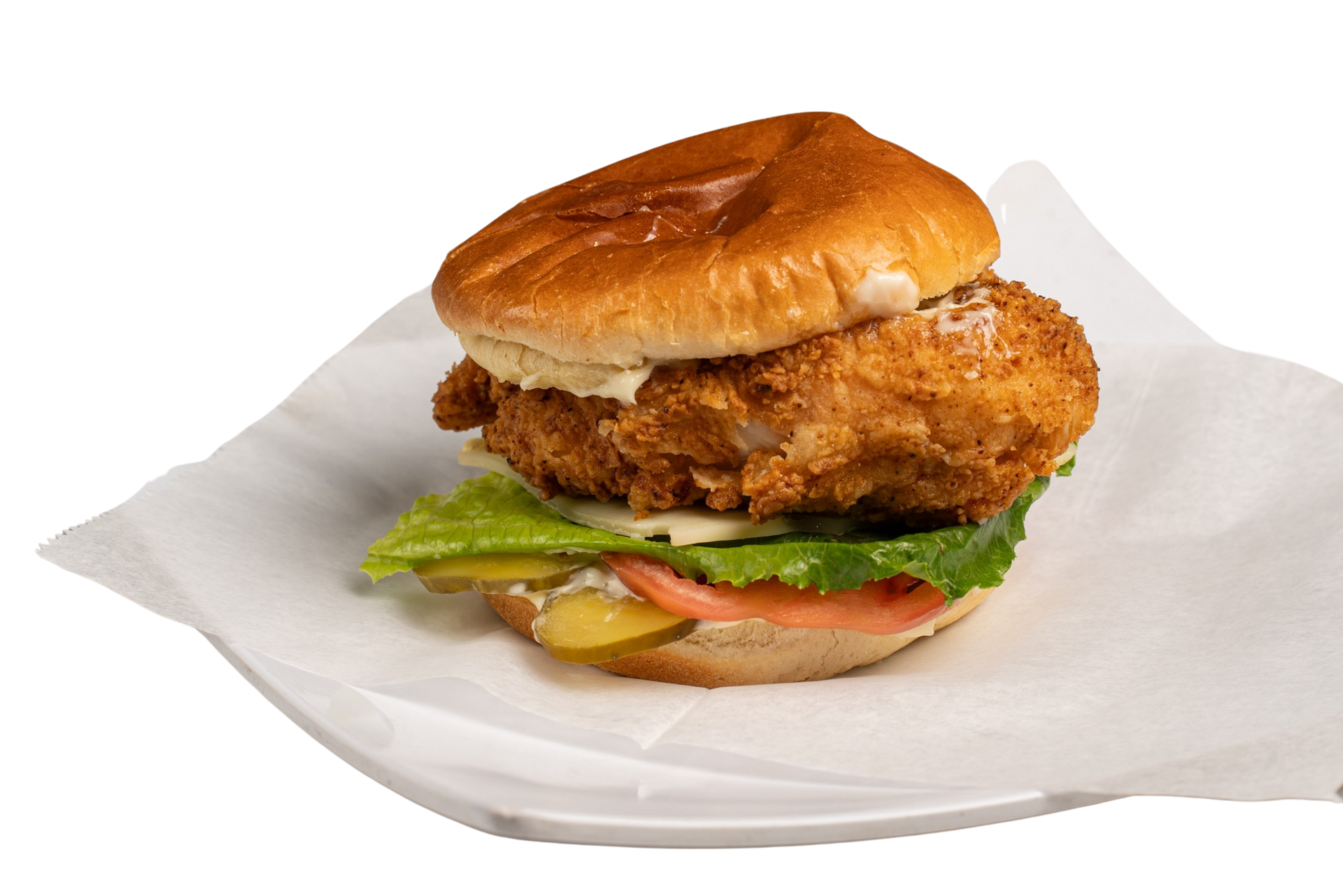 A fried chicken sandwich with lettuce , tomato and pickles on a white plate.