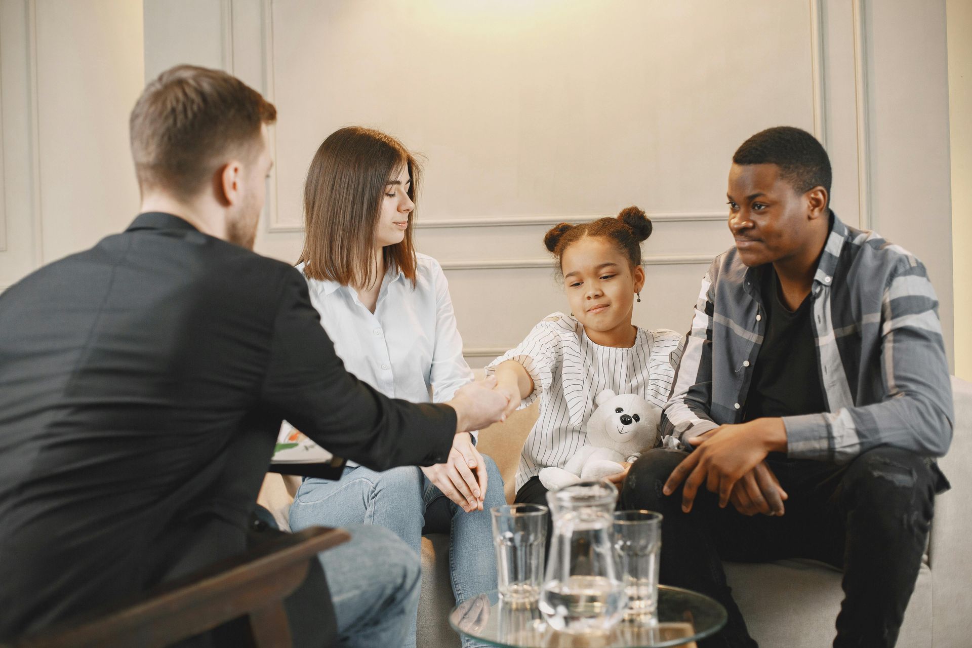 A family is sitting at a table talking to a man.
