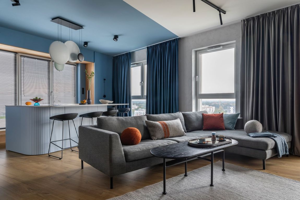 A living room with a couch , coffee table , and blue curtains.