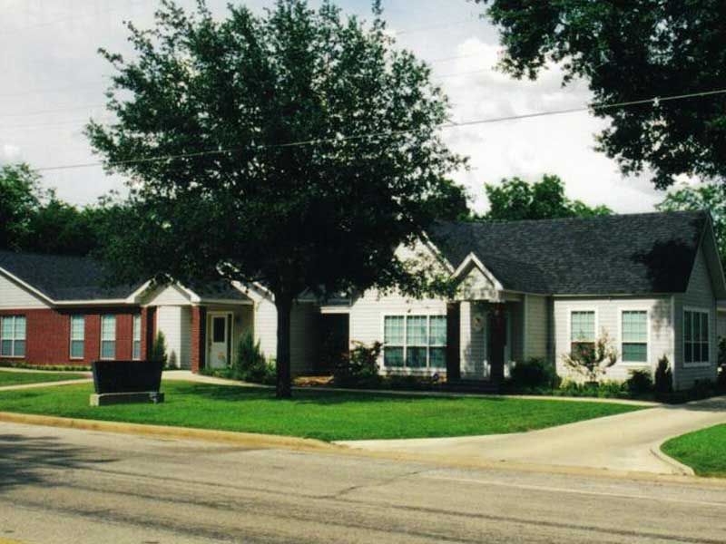 a white house with a black roof sits next to a red house