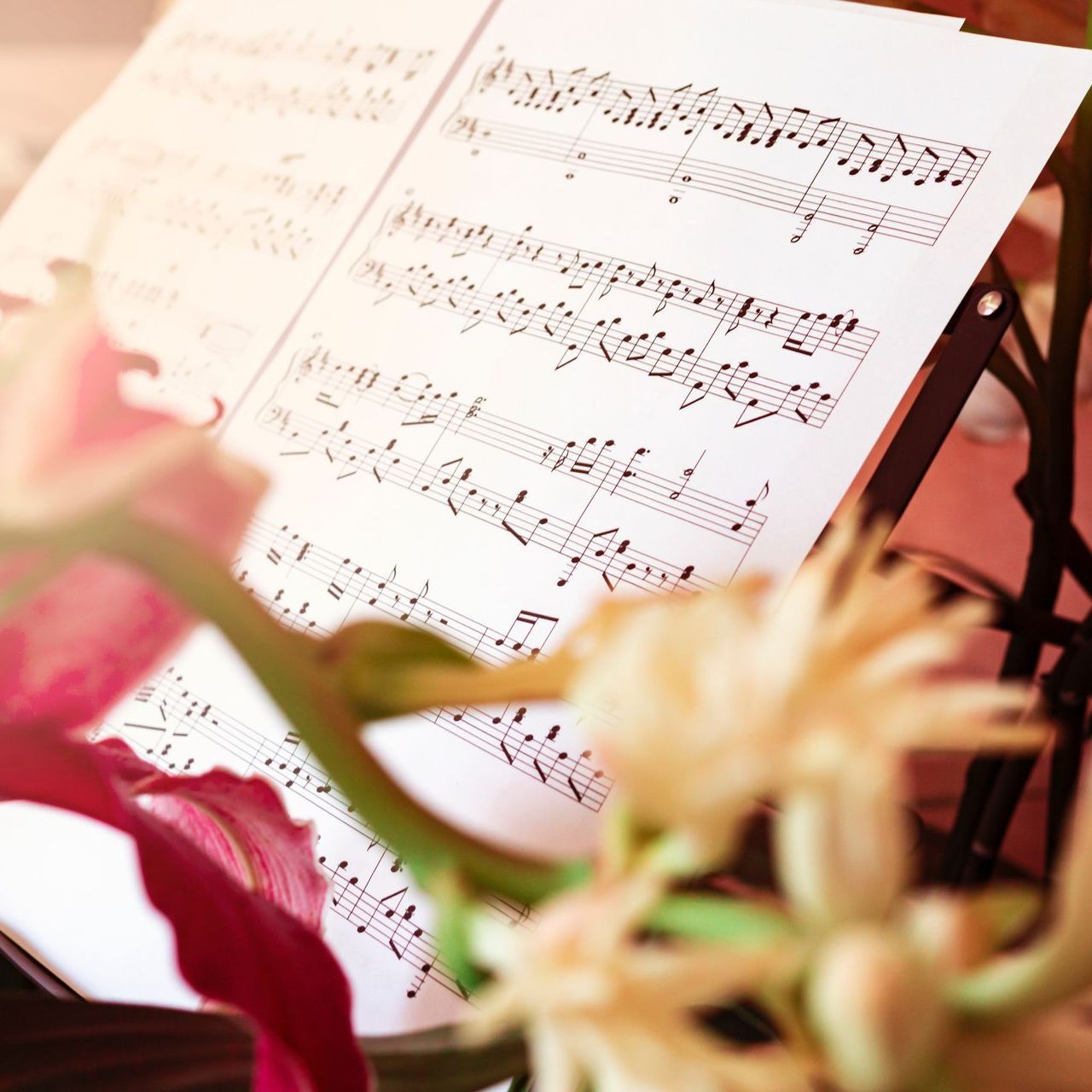 a close up of a sheet of music with a flower in the foreground