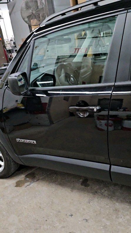 A black jeep renegade is parked in a parking lot.