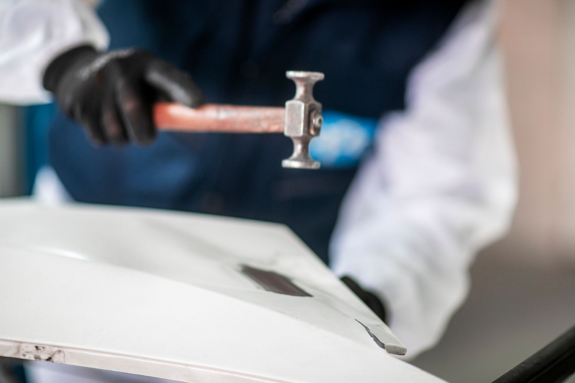 A man is using a hammer to fix a car door.