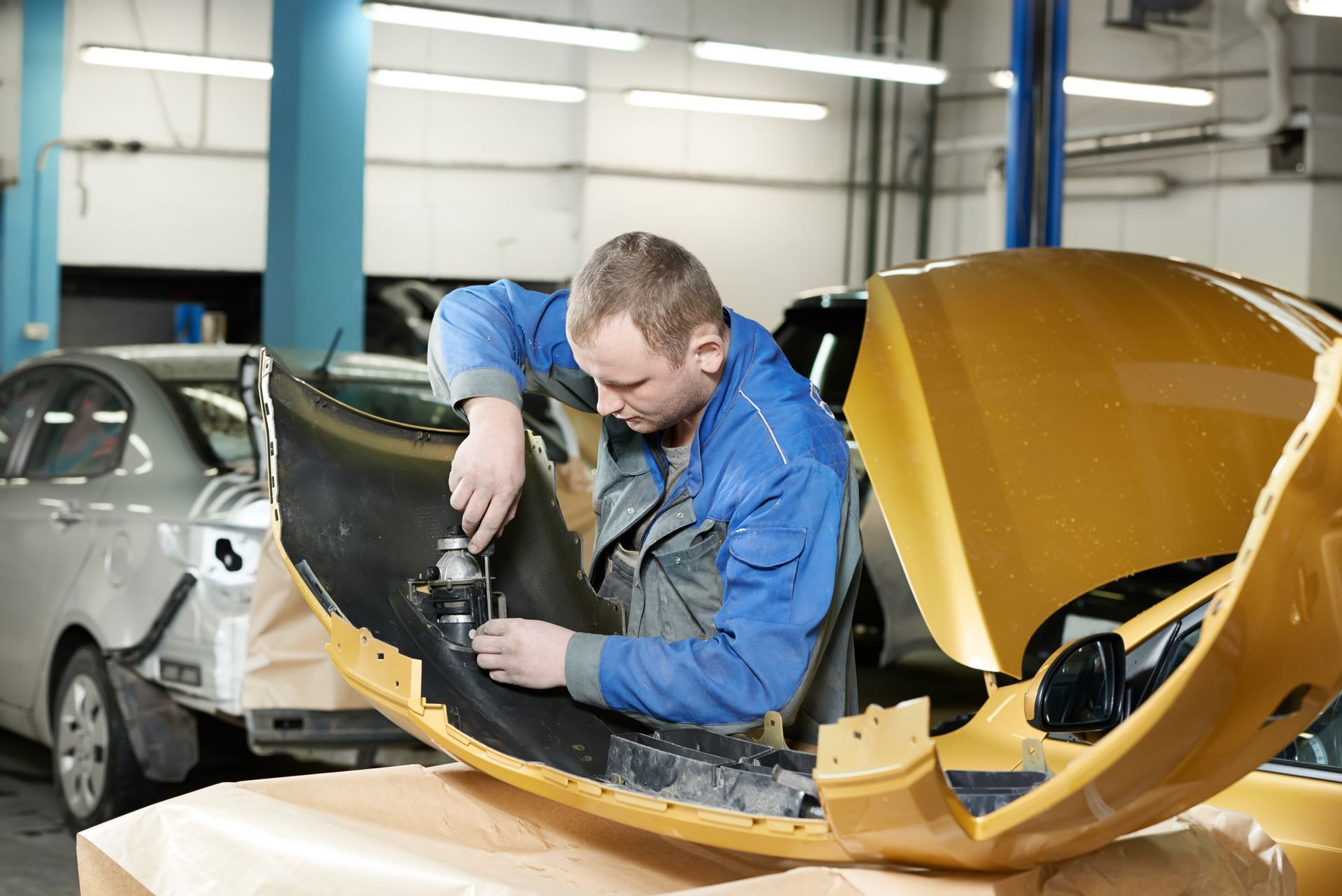 A man is working on a yellow car in a garage.