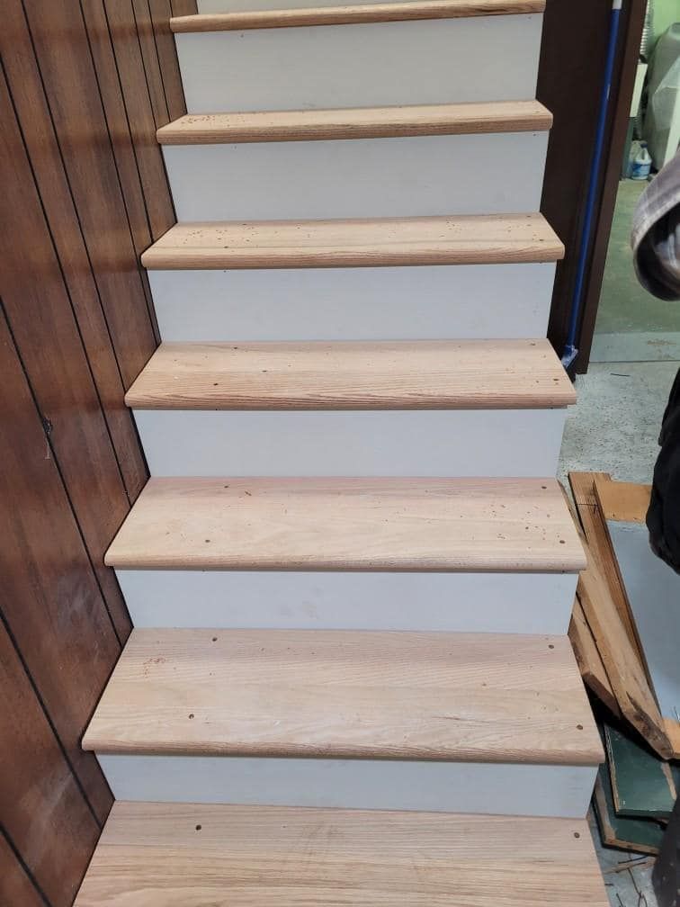 Wooden staircase with white risers and light wood treads.